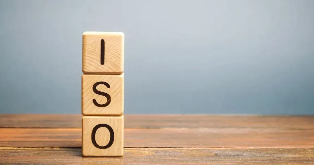 Three wooden dice stacked on a table, with letters spelling the word ISO from top to bottom