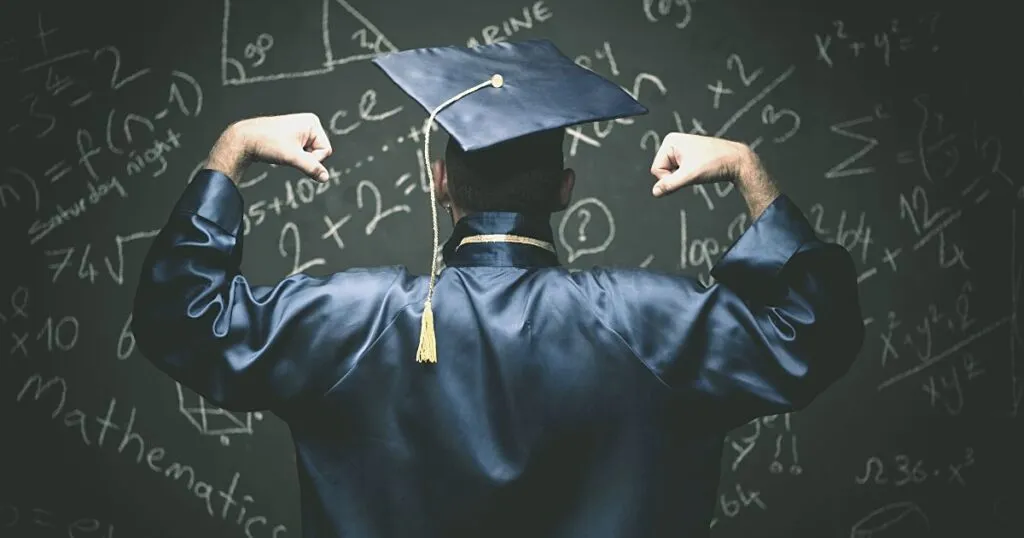Graduate in cap and gown, seen from behind, facing a blackboard full of calculations