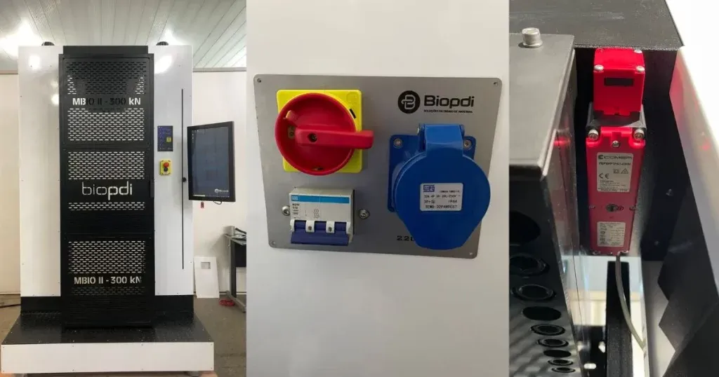 Biopdi 300 kN universal testing machine with the emergency stop button on the column panel, power supply plate with main switch, circuit breaker and industrial socket, and an internal detail of the machine