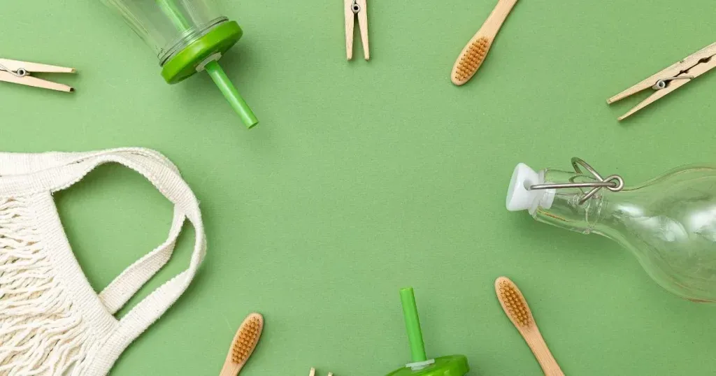 Bamboo toothbrushes, wooden clothespins, a cotton mesh bag and glass bottles on a green background
