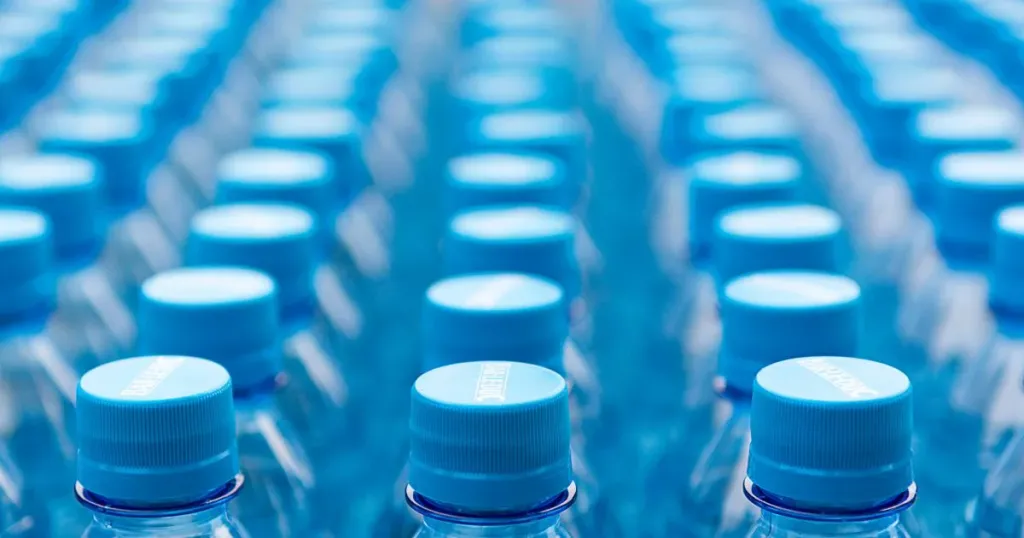 Plastic water bottles with blue caps lined up in rows
